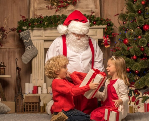 Father Christmas giving gifts to two children.