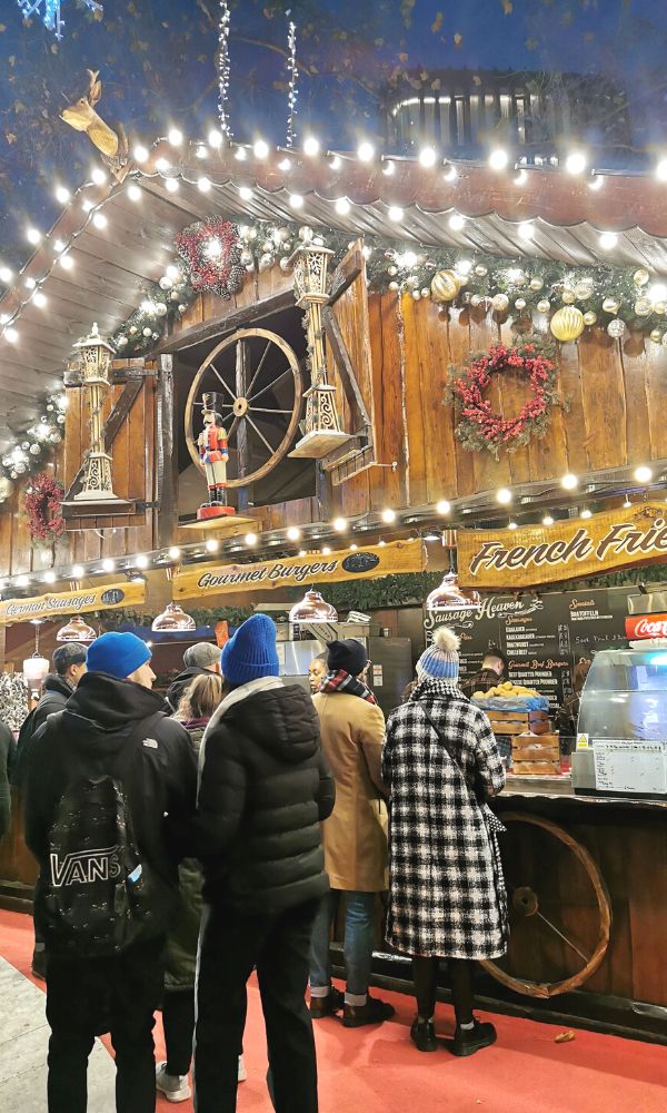 People standing by a stall at a Christmas market.