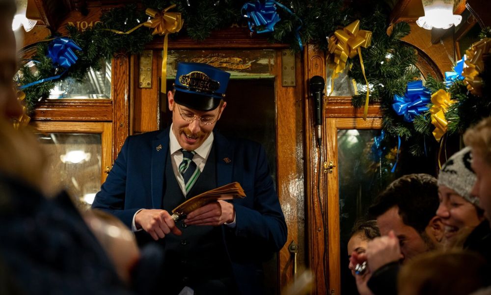 Conductor clipping a golden ticket on the Seaton Tramway Polar Express train ride in the UK.