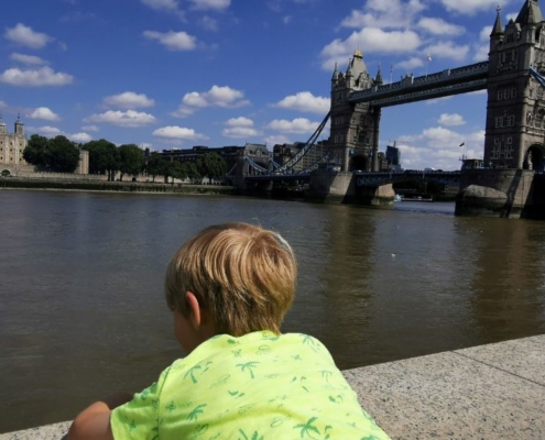 Boy in a yellow tshirt looking out over Tower Bridge and the Tower of London.