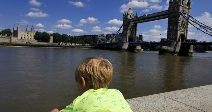 Boy in a yellow tshirt looking out over Tower Bridge and the Tower of London.