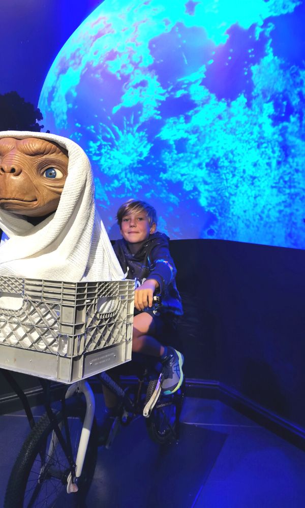 Boy sitting on a bike with ET in the basket with a full moon in the background at Madame Tussauds in London.