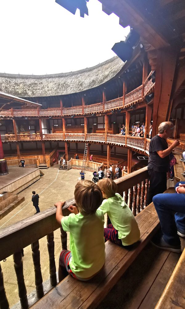 Family on a tour of the Globe Theatre in London with two boys in yellow tshirts looking at the stage.