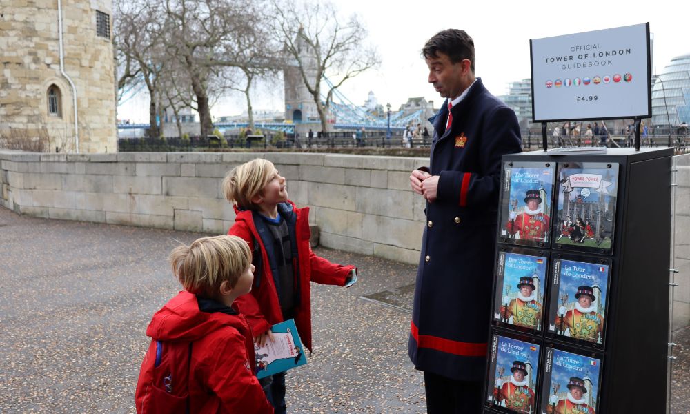 Kids talking to a guide book seller at the Tower of London - one of the most visited attractions for families in London.