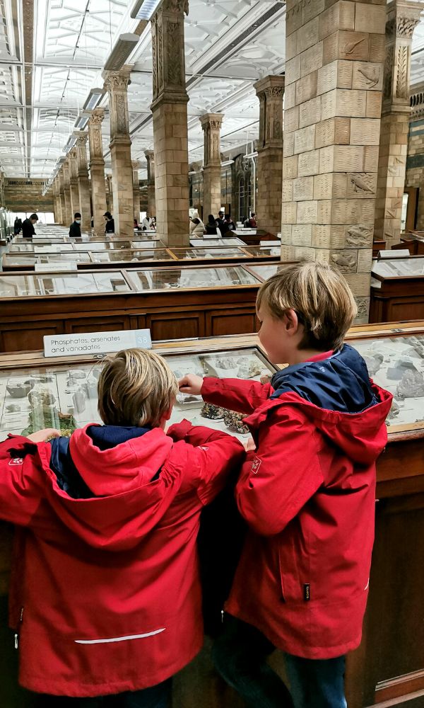 Two boys in red jackets looking at gems in the Natural History Museum in London - one of the best family days out in London.