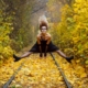 Lady in Halloween fancy dress jumping over train tracks with fallen autumn leaves.