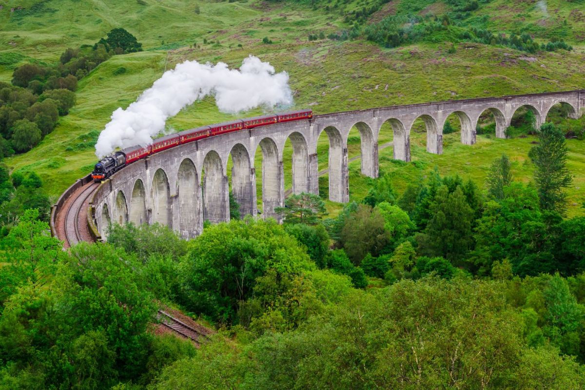 Jacobite Steam Train passing over the Glenfinnan Viaduct in Scotland - one of the best Harry Potter experiences in the UK.