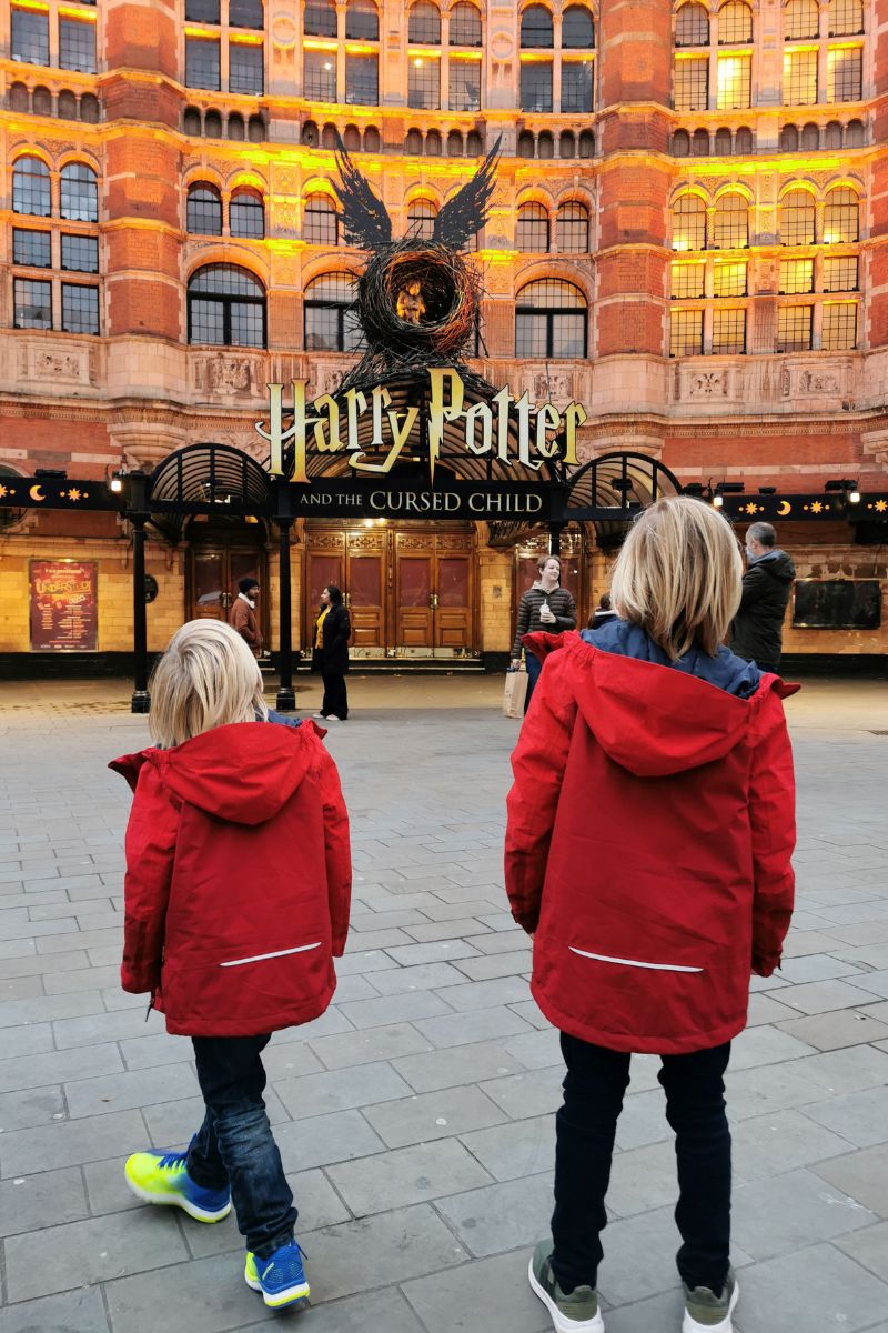 Two kids standing outside of Harry Potter and the Cursed Child in London.