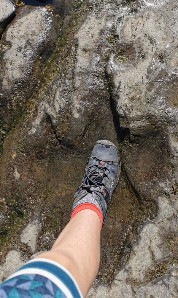 Child's foot in a dinosaur footprint on An Corran beach on the Isle of Skye in Scotland.