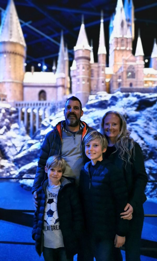Family of four standing in front of a snow covered Hogwarts at the WB Studios.