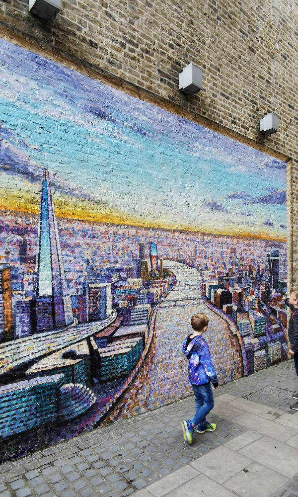 Kids looking at a mural of the London skyline.