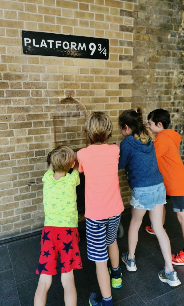 Kids trying to push the trolley through the wall at Platform 9 3-4 at Kings Cross Station.