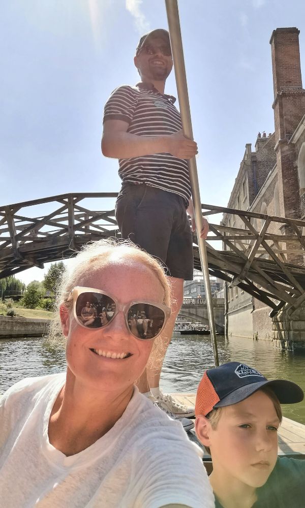 LAdy in sunglasses and boy in a cap on a punting trip in Cambridge on a sunny day. 