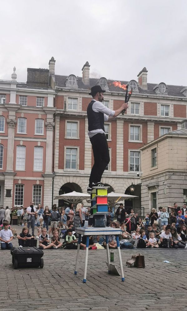 Street performer in Covent Garden standing on a table juggling fire.
