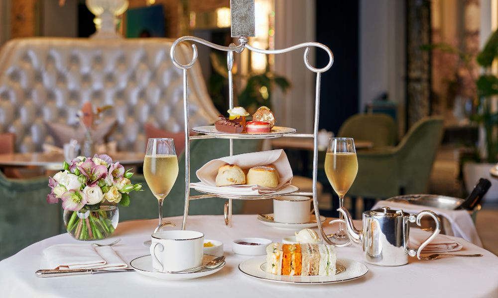 Traditional afternoon tea at The Langham in London with a fancy tea stand and two glasses of champagne.