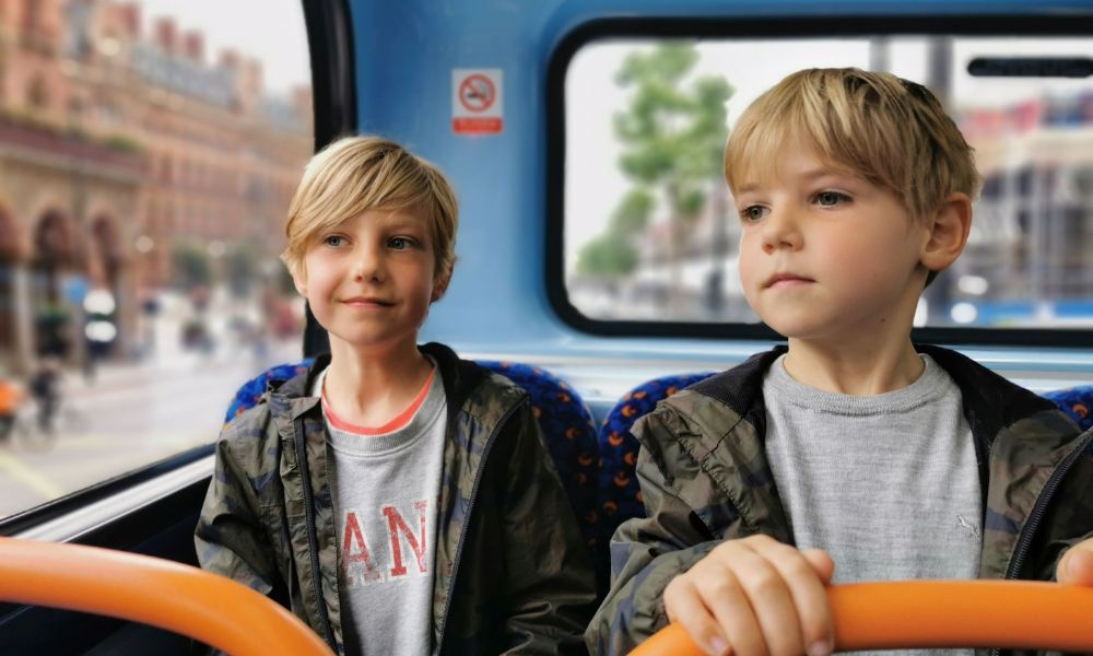 Two boys sightseeing from the top deck of a London bus.