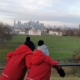 Two kids in red coats looking at one of the best free views of the London skyline from Greenwich Park.