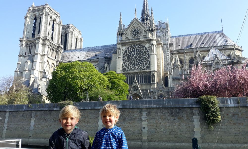 Two little boys sitting across the river from Notre Dame in Paris during one of the most exciting day trips from London for families we've ever done.