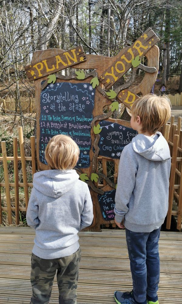 Boys looking at a notice board detailing events at BeWILDerwood in Norfolk.